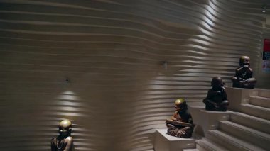 Heykeller dalgalı duvarların karşısında sessizce oturuyorlar.