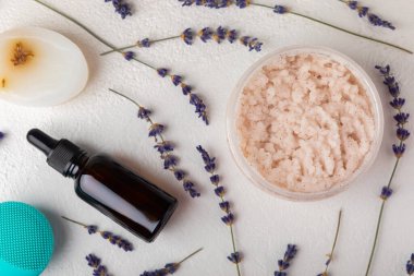 Kaplıca. Lavanta çiçekleri, kokulu mum, vücut kremi, gerekli yağ, fırça ve el yapımı sabun. Beyaz desenli lavanta çiçekli doğal bitkisel kozmetikler.