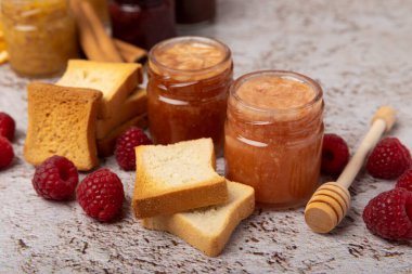 Reçelli tost ekmeği. Bir kavanoz ahududu reçeli. Masada kahvaltıda verilen tatlı reçelli lezzetli tost. Dokulu arka planda nefis tostlar. Mesaj için yer var. Kopyalamak için yer.