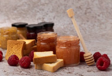 Reçelli tost ekmeği. Bir kavanoz ahududu reçeli. Masada kahvaltıda verilen tatlı reçelli lezzetli tost. Dokulu arka planda nefis tostlar. Mesaj için yer var. Kopyalamak için yer.