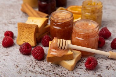 Reçelli tost ekmeği. Bir kavanoz ahududu reçeli. Masada kahvaltıda verilen tatlı reçelli lezzetli tost. Dokulu arka planda nefis tostlar. Mesaj için yer var. Kopyalamak için yer.