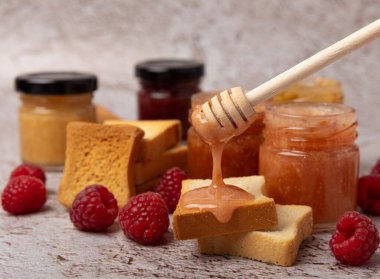 Reçelli tost ekmeği. Bir kavanoz ahududu reçeli. Masada kahvaltıda verilen tatlı reçelli lezzetli tost. Dokulu arka planda nefis tostlar. Mesaj için yer var. Kopyalamak için yer.
