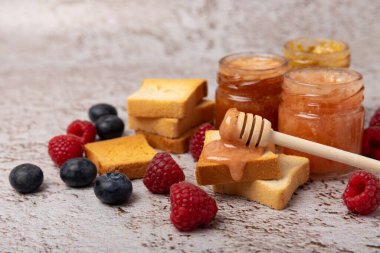 Reçelli tost ekmeği. Bir kavanoz ahududu reçeli. Masada kahvaltıda verilen tatlı reçelli lezzetli tost. Dokulu arka planda nefis tostlar. Mesaj için yer var. Kopyalamak için yer.