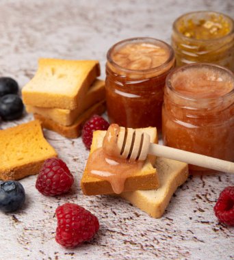 Reçelli tost ekmeği. Bir kavanoz ahududu reçeli. Masada kahvaltıda verilen tatlı reçelli lezzetli tost. Dokulu arka planda nefis tostlar. Mesaj için yer var. Kopyalamak için yer.