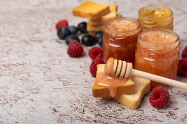 Reçelli tost ekmeği. Bir kavanoz ahududu reçeli. Masada kahvaltıda verilen tatlı reçelli lezzetli tost. Dokulu arka planda nefis tostlar. Mesaj için yer var. Kopyalamak için yer.