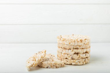 Beyaz ahşap bir masada yuvarlak pirinç kekleri. Kıtır ekmek. Pofuduk pirinç ekmeği. Diyet gevrek pirinç kekleri. Mesaj için uygun bir yer. Kopyalamak için yer. Sağlıklı yiyecekler. diyet ürünü.