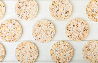 Beyaz ahşap bir masada yuvarlak pirinç kekleri. Kıtır ekmek. Pofuduk pirinç ekmeği. Diyet gevrek pirinç kekleri. Mesaj için uygun bir yer. Kopyalamak için yer. Sağlıklı yiyecekler. diyet ürünü.