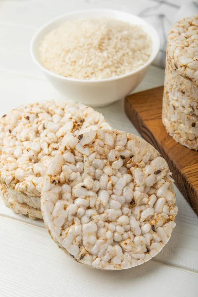 Round rice cakes and a plate of rice on a white wooden table. Crispbread.Puffed rice bread. diet crispy round rice cakes.Place for text. Place for copy. Healthy food. dietary product.