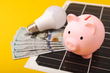 Güneş paneli, lamba, kumbara ve para. Yenilenebilir enerjinin ekonomik faydalarını hesapla. Düz bileşim. Yeşil enerji kavramı.