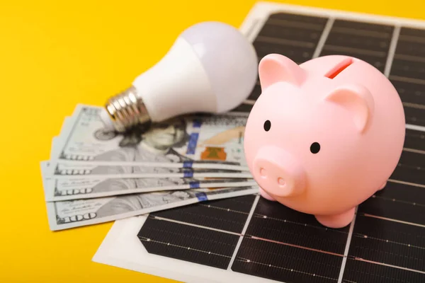 Solar panel with led lamp, piggy bank and money. Concept Economic benefits of renewable energy.Flat composition.green energy concept.