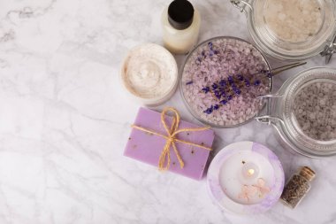 Lavanta çiçekleri, kokulu deniz tuzu, vücut kremi ve mum. Spa, güzellik ve sağlık salonu, cilt bakım kozmetiği. Doğal kozmetik. Roma prosedürleri. Beyaz mermer arka planda yakın plan.