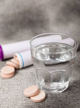 Fışkırtıcı tablet ve siyah desenli arka planda bir bardak su. Vitaminler. Sağlık konsepti. Dokunulmazlık ilacı. Kopya için yer var. Metin için boşluk.