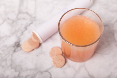 Beyaz mermer arka planda, bir bardak suyun içinde fıs fıs tablet. Vitaminler. Sağlık konsepti. Dokunulmazlık ilacı. Kopya için yer var. Metin için boşluk.