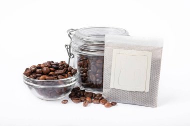 Beyaz arka planda izole edilmiş kahve çekirdekli taze kahve torbası. Fincanda demlenmek için öğütülmüş kahve.