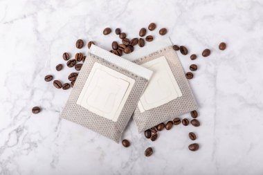 Evde kahve yapma modası. Kahverengi arka planda kahve çekirdekleri olan bir bardakta taze içecek damlatın. Fincanda demlenmek için öğütülmüş kahve. Kahveyi kağıt tipi filtre kullanarak damlat.