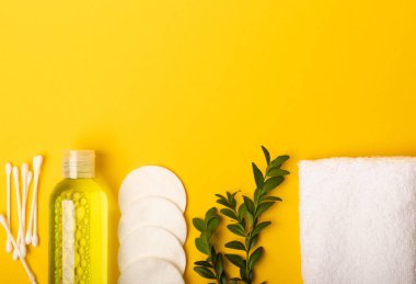 Micellar temizleyici su, pamuklu bez, havlu ve diskler, kozmetik ürünleri çıkarmak ve sarı arkaplandaki sebiyumun derisini temizlemek için. Güzellik konsepti. Cilt bakımı. Mesaj için yer. MOCAPS FLETLEY