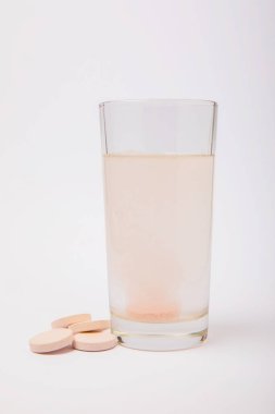 Portakal aromalı C vitamini hapları beyaz arka planda izole edilmiş bir bardak suda erir. Sağlık kavramı. Tıp konsepti.