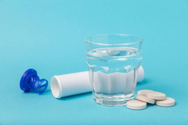 Öfkeli bir vitamin tableti mavi arka plandaki bir bardak suyun içinde düşer ve çözülür. Sağlık kavramı. Tıp konsepti. Metin için yer.