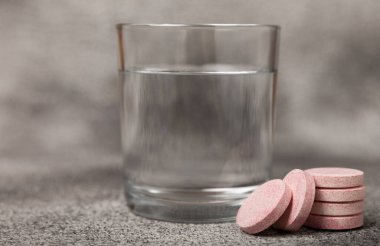 Coşkulu bir vitamin tableti siyah mermer arka planda bir bardak suyun içinde düşer ve çözülür. Sağlık kavramı. Tıp konsepti. Metin için yer.