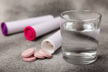 Coşkulu bir vitamin tableti siyah mermer arka planda bir bardak suyun içinde düşer ve çözülür. Sağlık kavramı. Tıp konsepti. Metin için yer.