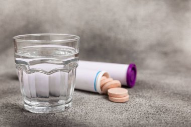 Coşkulu bir vitamin tableti siyah mermer arka planda bir bardak suyun içinde düşer ve çözülür. Sağlık kavramı. Tıp konsepti. Metin için yer.