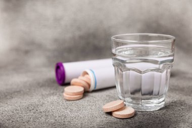 Coşkulu bir vitamin tableti siyah mermer arka planda bir bardak suyun içinde düşer ve çözülür. Sağlık kavramı. Tıp konsepti. Metin için yer.