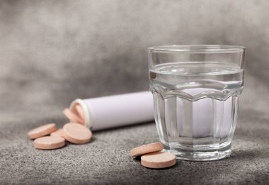 Coşkulu bir vitamin tableti siyah mermer arka planda bir bardak suyun içinde düşer ve çözülür. Sağlık kavramı. Tıp konsepti. Metin için yer.