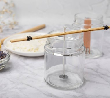 Ev yapımı beyaz çevre dostu mumlar, cam, fitil, beyaz mermer üzerine parfüm. Hobi, iş. Kendi ellerinle mum yapıyorsun. Vejetaryen ürünü. Boşluğu kopyala.