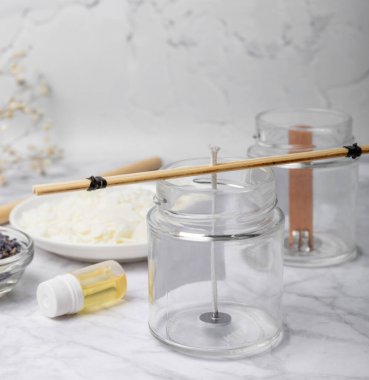 Ev yapımı beyaz çevre dostu mumlar, cam, fitil, beyaz mermer üzerine parfüm. Hobi, iş. Kendi ellerinle mum yapıyorsun. Vejetaryen ürünü. Boşluğu kopyala.