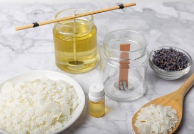 Ev yapımı beyaz çevre dostu mumlar, cam, fitil, beyaz mermer üzerine parfüm. Hobi, iş. Kendi ellerinle mum yapıyorsun. Vejetaryen ürünü. Boşluğu kopyala.