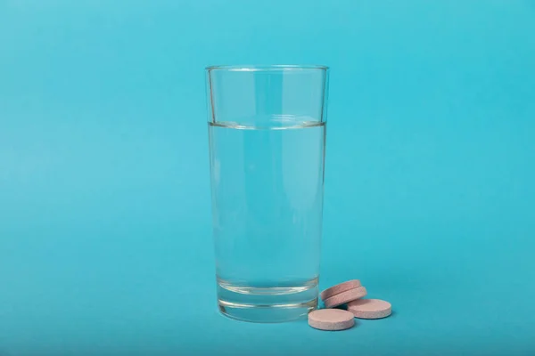 Öfkeli Bir Vitamin Tableti Mavi Arka Plandaki Bir Bardak Suyun — Stok fotoğraf