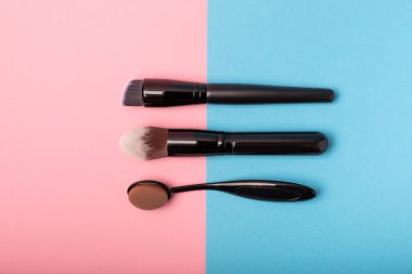 Pembe-mavi arka planda makyaj için makyaj fırçası. Makyaj için kozmetik ürün. Yaratıcı ve güzel moda konsepti. Moda. Kozmetik makyaj fırçası koleksiyonu, üst görüş, afiş. Mesaj için yer. MOCAP.