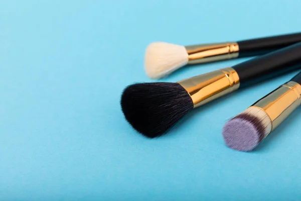 Cosmetic brush for makeup on a blue background. Cosmetic product for make-up. Creative and beauty fashion concept. Fashion. Collection of cosmetic makeup brushes, top view, banner.Place for text. MOCAP.