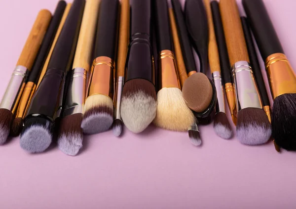 Cosmetic brush for make-up on a lilac background. Cosmetic product for make-up. Creative and beauty fashion concept. Fashion. Collection of cosmetic makeup brushes, top view, banner.Place for text.