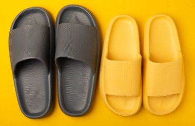 Sarı arka planda parlak lastik terlikler. Yaz tatili. Kapalı ayakkabılar. Mesaj için yer. YÜKSEL LAY