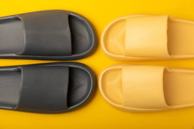 Sarı arka planda parlak lastik terlikler. Yaz tatili. Kapalı ayakkabılar. Mesaj için yer. YÜKSEL LAY