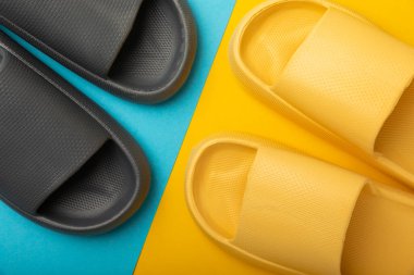 Sarı-mavi arka planda parlak lastik terlikler. Yaz tatili. Kapalı ayakkabılar. Mesaj için yer. YÜKSEL LAY