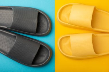 Sarı-mavi arka planda parlak lastik terlikler. Yaz tatili. Kapalı ayakkabılar. Mesaj için yer. YÜKSEL LAY