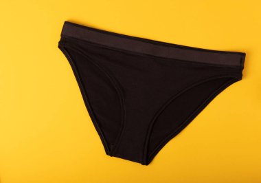 Kadın iç çamaşırı. Sarı arka planda farklı kadın iç çamaşırları. Bir insan için bir parça kıyafet. Yukarıdan bak. metin için yer.