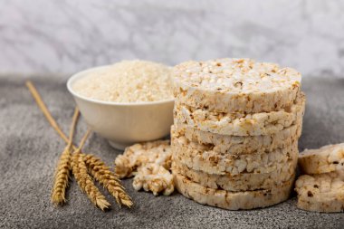 Pirinç kekleri siyah dokuma masasında, bir tabak pirincin arka planında. Yakın plan. Sağlıklı yiyecekler. Diyet yemek..