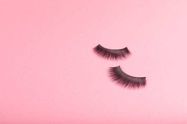 Pembe arka planda sahte kirpikler. Düz çizgi. Güzellik ve moda konsepti. Kirpik uzatma. Güzellik endüstrisi. Mesaj için yer. Kopyalanacak yer.
