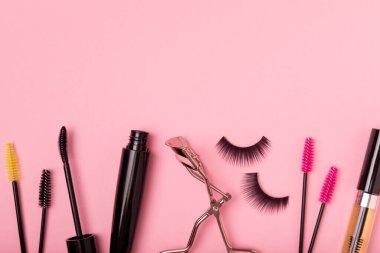 Takma kirpikler, rimel ve kirpik fırçaları, pembe arka planda kirpik bigudileri. Makyaj aletleri. Güzellik konsepti. Makyaj. Mesaj için yer. Kopyalama yeri. Düz çizgi. MOCAP.