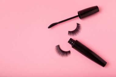 Takma kirpikler, rimel ve kirpik fırçaları, pembe arka planda kirpik bigudileri. Makyaj aletleri. Güzellik konsepti. Makyaj. Mesaj için yer. Kopyalama yeri. Düz çizgi. MOCAP.