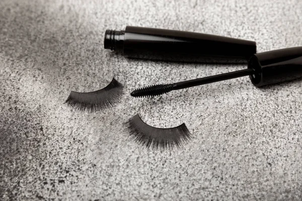 Composition with false eyelashes, mascara and eyelash brushes, eyelash curlers on a black textured background. Makeup artist tools. Beauty concept. Makeup. Place for text. Place for copying. Flatley. MOCAP.