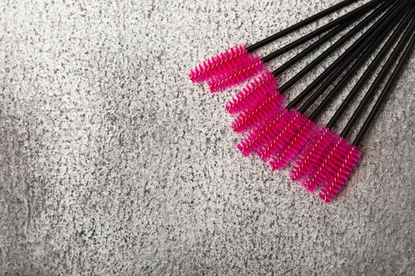 Eyelash extension brushes on a black marble background. Brush for combing extended and false eyelashes. Brush for straightening eyelashes and eyebrows.