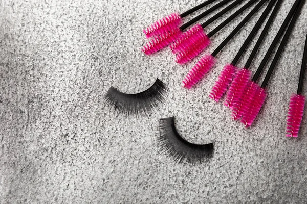 Eyelash extension brushes on a black marble background. Brush for combing extended and false eyelashes. Brush for straightening eyelashes and eyebrows.
