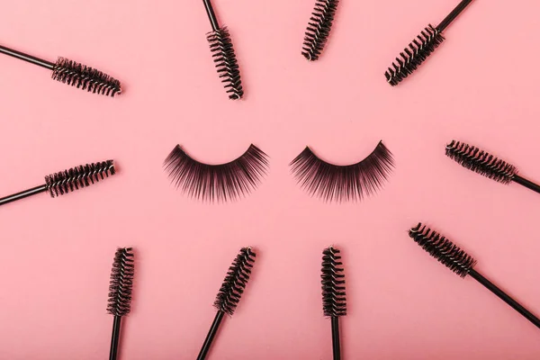 Composition with false eyelashes, mascara and eyelash brushes, eyelash curlers on a pink background. Makeup artist tools. Beauty concept. Makeup. Place for text. Place for copying. Flatley. MOCAP.