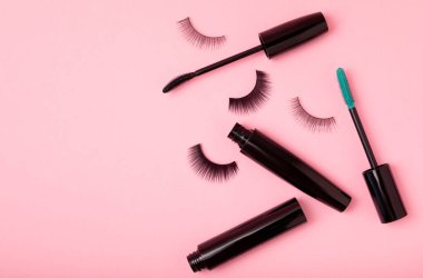 Takma kirpikler, rimel ve kirpik fırçaları, pembe arka planda kirpik bigudileri. Makyaj aletleri. Güzellik konsepti. Makyaj. Mesaj için yer. Kopyalama yeri. Düz çizgi. MOCAP.