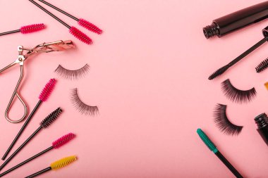Takma kirpikler, rimel ve kirpik fırçaları, pembe arka planda kirpik bigudileri. Makyaj aletleri. Güzellik konsepti. Makyaj. Mesaj için yer. Kopyalama yeri. Düz çizgi. MOCAP.