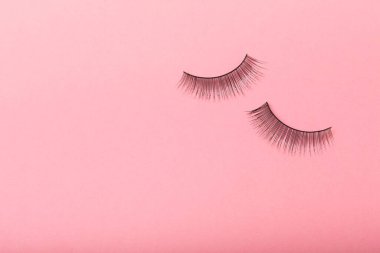 Pembe arka planda sahte kirpikler. Düz çizgi. Güzellik ve moda konsepti. Kirpik uzatma. Güzellik endüstrisi. Mesaj için yer. Kopyalanacak yer.